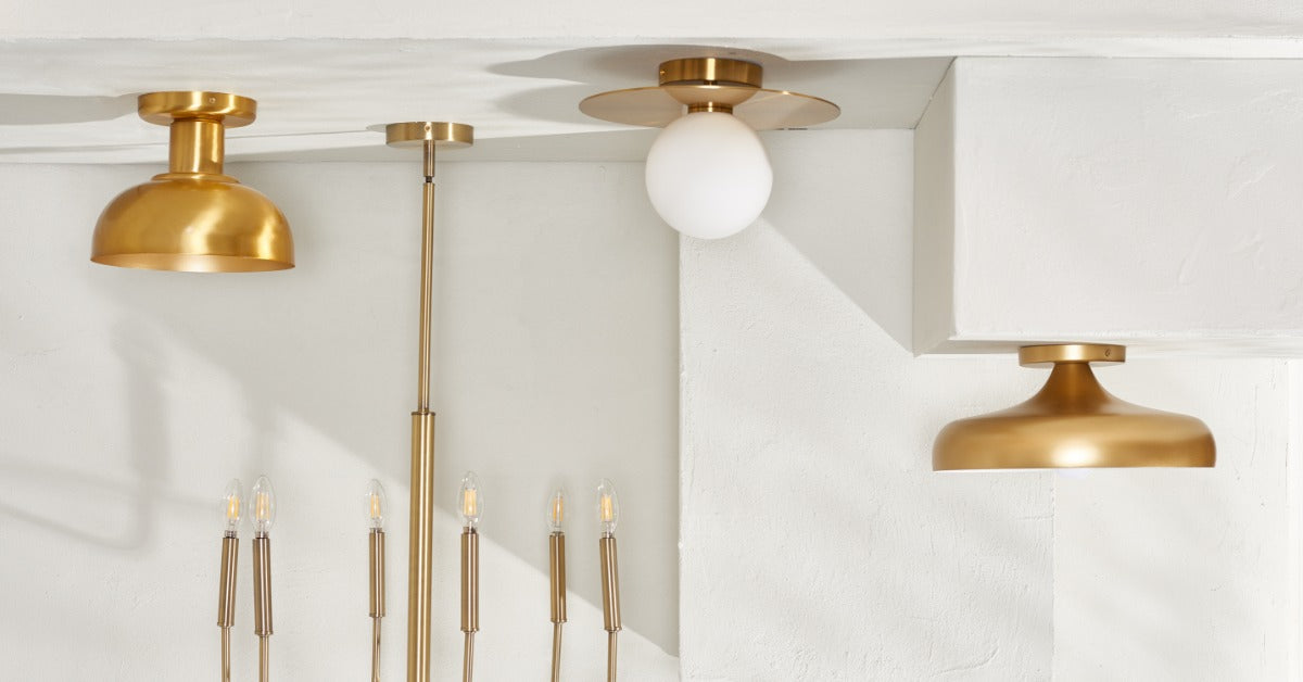 A group of gold ceiling lights, wall sconces, and hanging bulbs arranged against white textured walls.